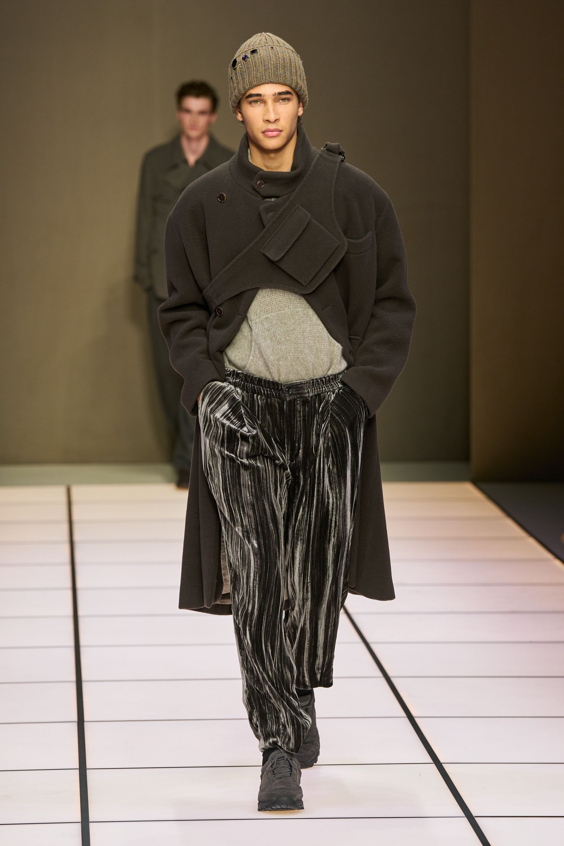 Giorgio Armani 26FW 男装回归品牌最本质的语言：流动、克制与永恒。柔软大衣、宽松长裤、针织与轻结构西装在灰、驼、米与墨绿中缓慢展开，强调身体与面料之间的自然关系。系列几乎不依赖任何戏剧化装饰，却通过比例、步伐与质感建立权威感，是对“真正优雅无需证明”的再次确认，也是一种对快节奏时尚的温和抵抗-顽石频道趋势研究